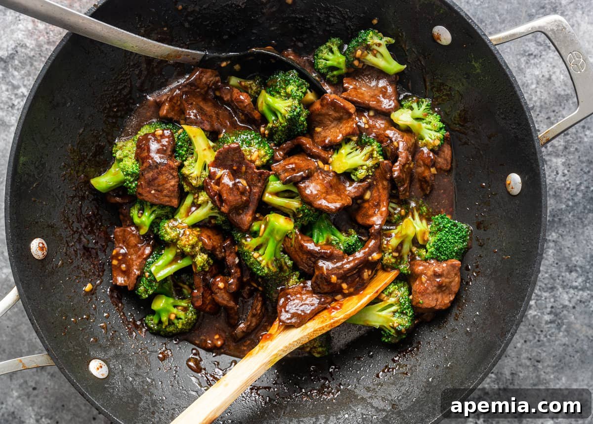 overhead shot of broccoli beef stir frying in a traditional wok