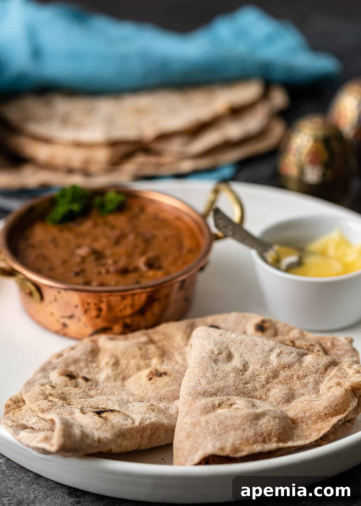 Closeup side view of a white plate with perfectly cooked Chapati, elegantly folded and ready to serve, highlighting its inviting texture.