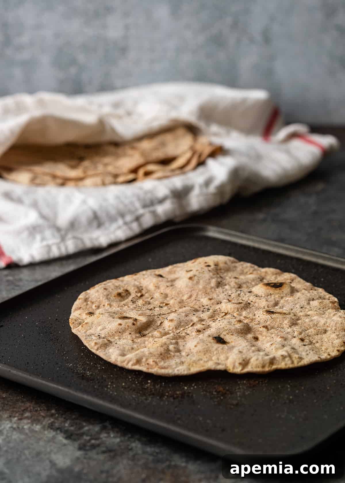 Closeup side view of Indian flatbread (Roti) actively cooking and puffing up on a hot skillet, illustrating the transformation of the dough.