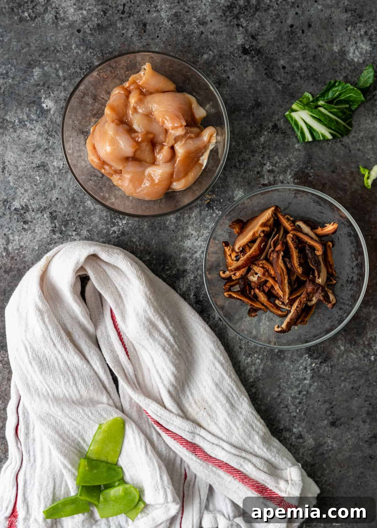 Uncooked ingredients for Sizzling Rice Soup, neatly arranged in bowls on a white towel