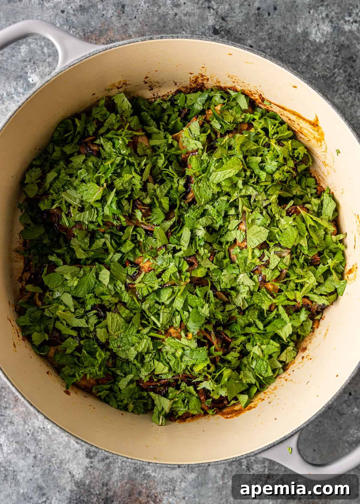 overhead process shot: adding mint and cilantro to pan