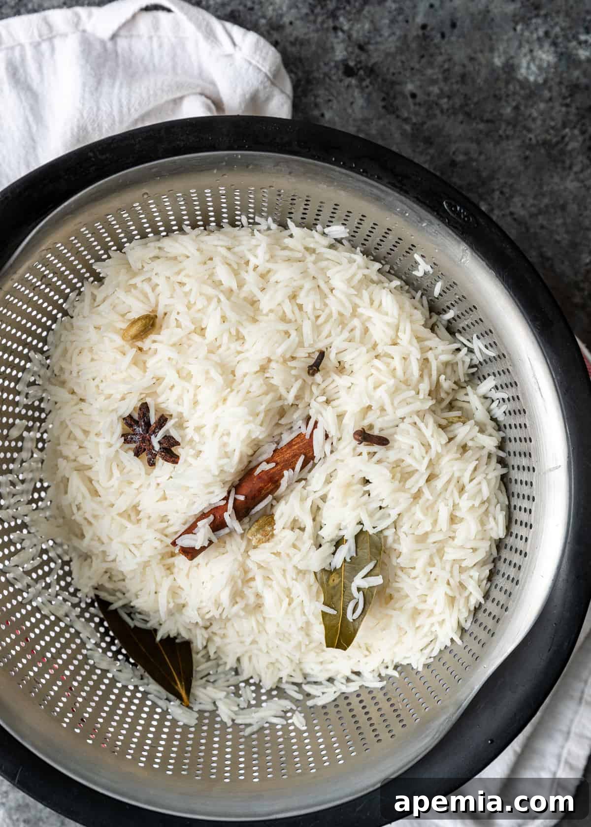 overhead process shot: cooked rice in a colander for my chicken biryani recipe