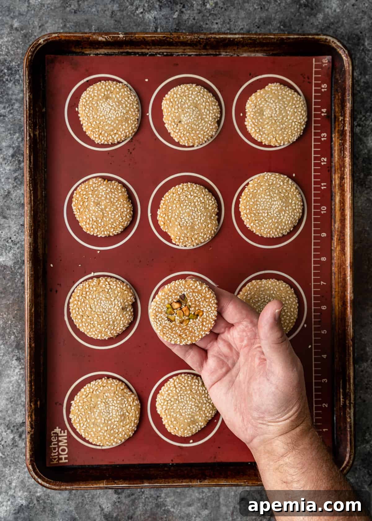 overhead process shot: baking sheet and hand holding one of the cookie