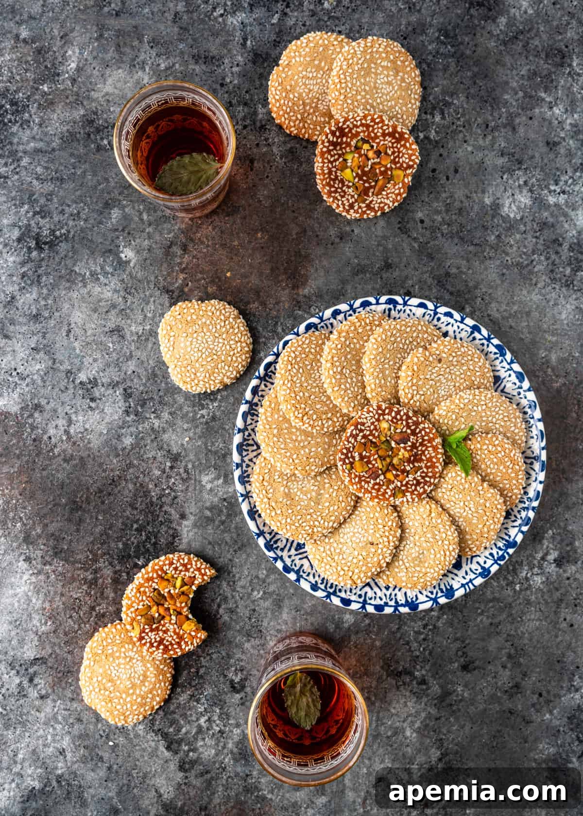 overhead: blue and white plate with sesame seed cookie with a few cookies scattered on counter 