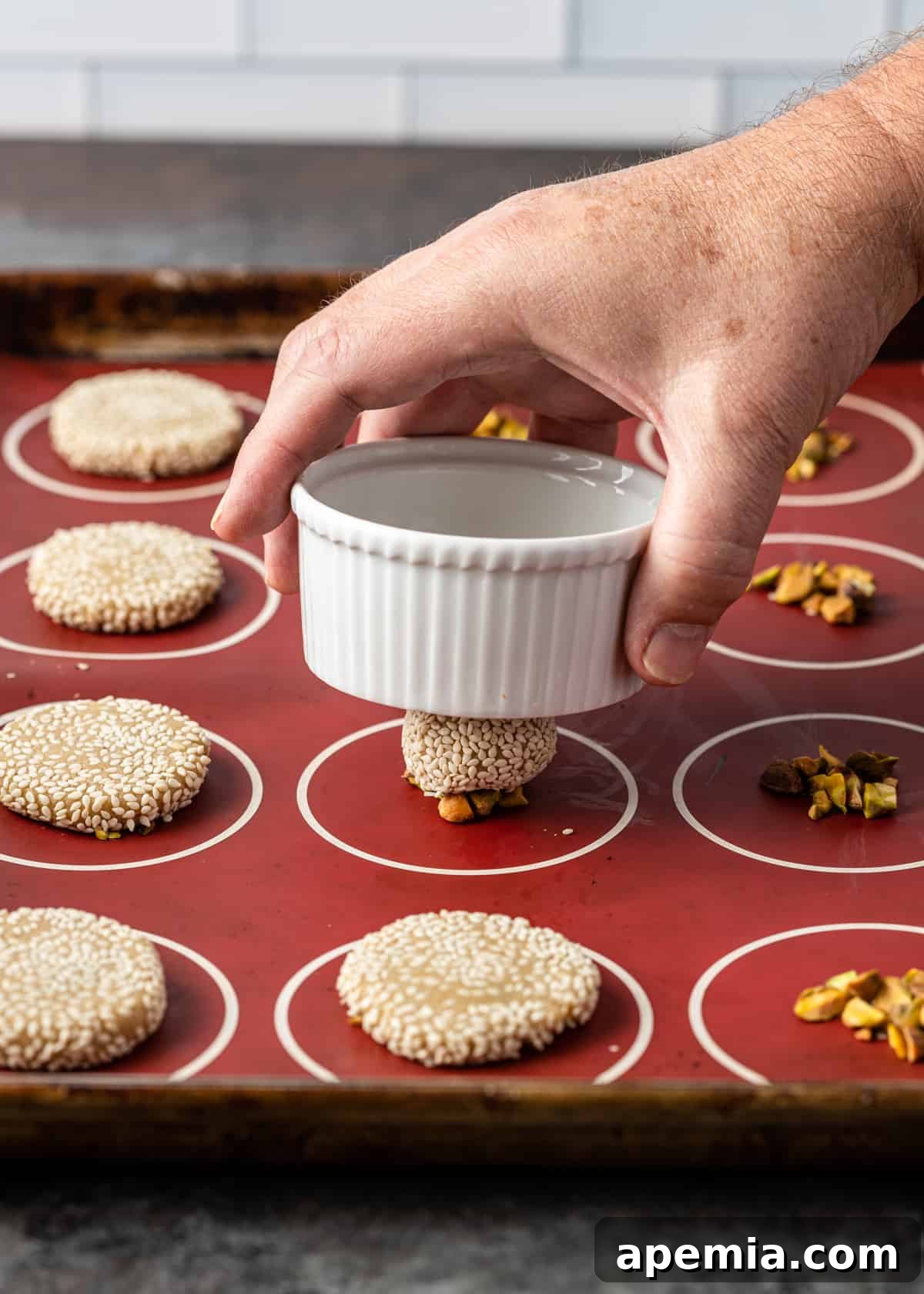 closeup side view process shot: hand placing small bowl on top of cookie dough