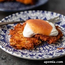 The ultimate crispy potato latkes recipe, garnished with sour cream and applesauce, ready to be served.
