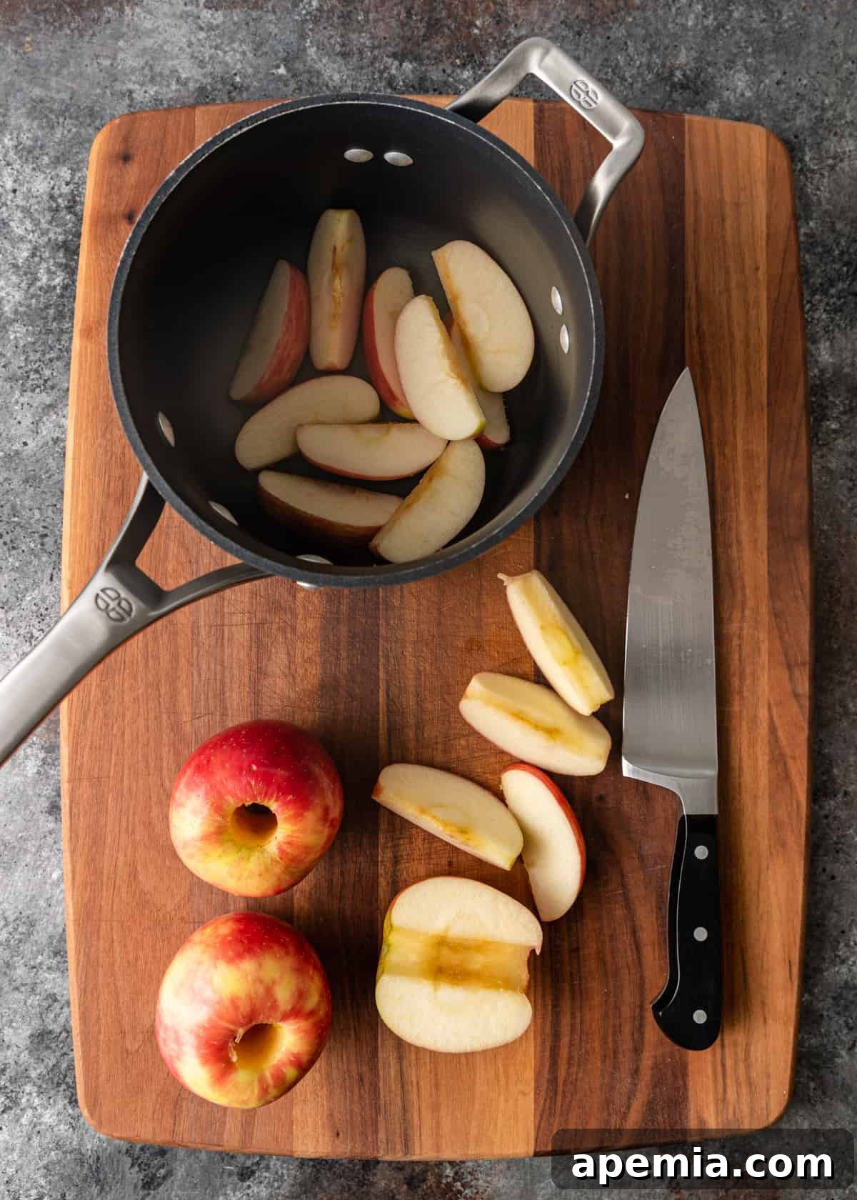 Overhead process shot demonstrating how to core and cut fresh apples into even slices for homemade applesauce.