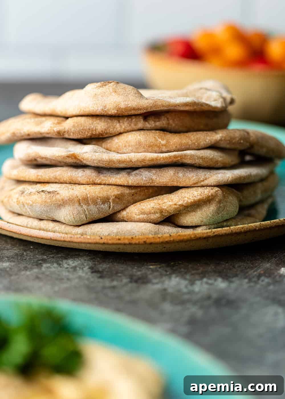 A stack of golden, perfectly puffed homemade pita bread on a ceramic plate, a testament to successful baking.