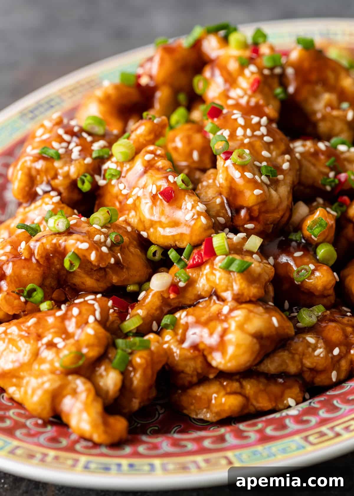 closeup side view: sauced honey chicken on colorful platter