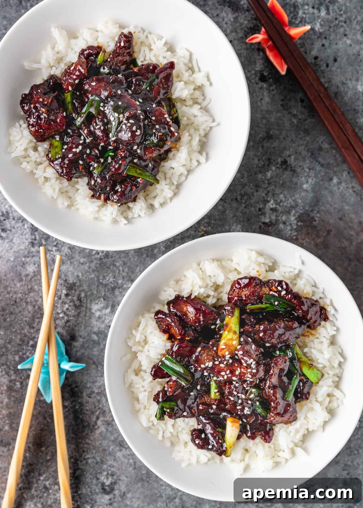 overhead: two white plates with mongolian beef stir fry on bed of rice