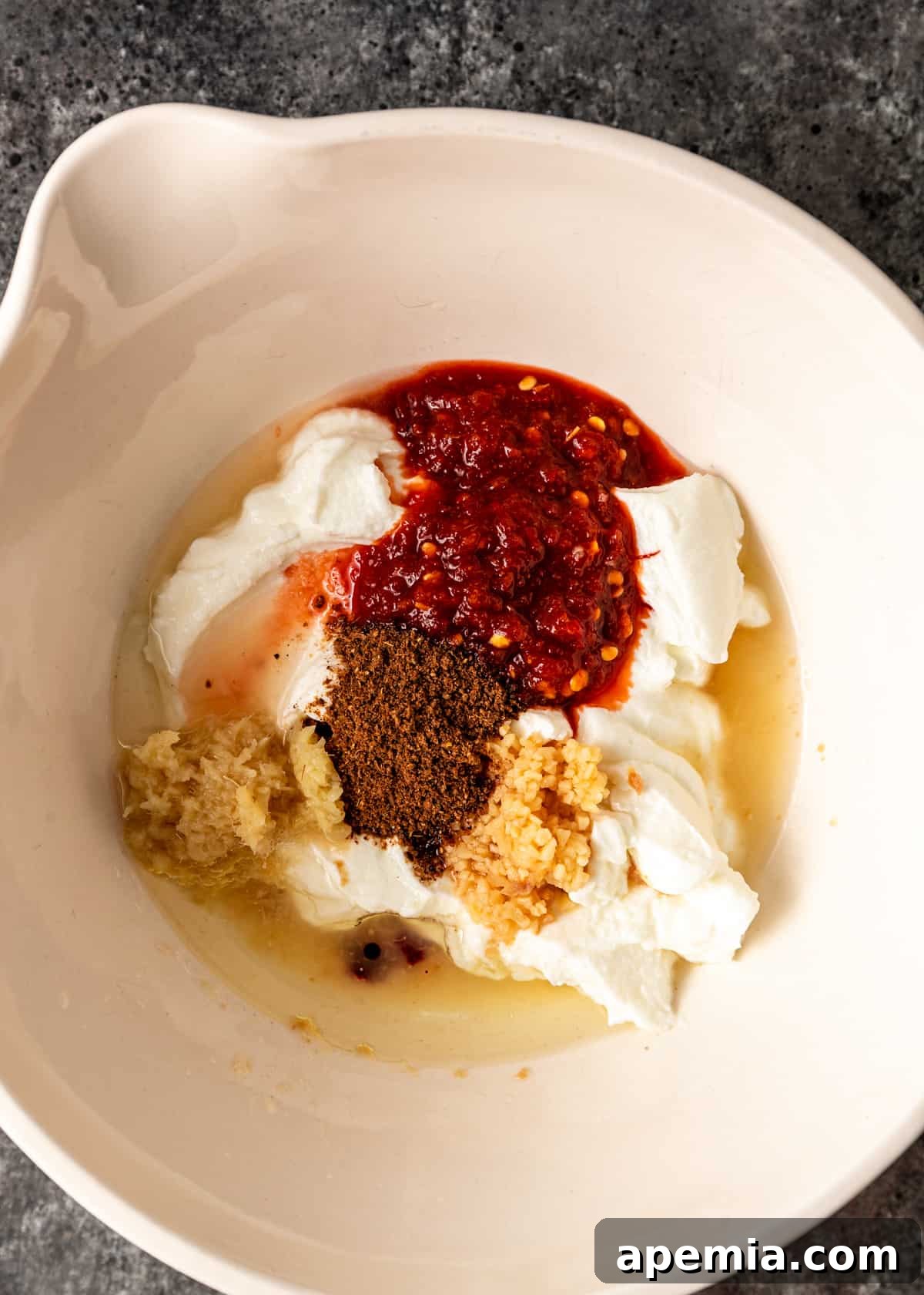 Bowl showing a blend of vibrant spices and yogurt for the Tandoori Chicken marinade