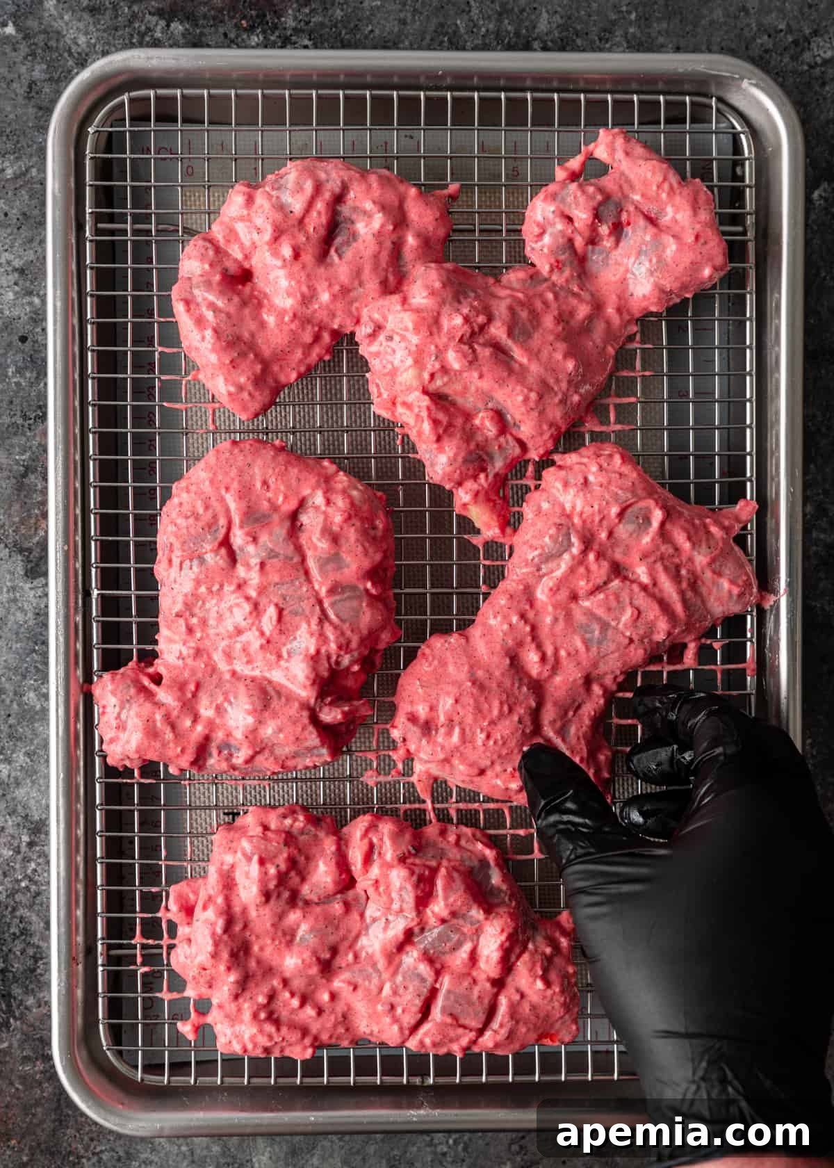 Chicken thighs soaking in a rich, red tandoori marinade in a bowl