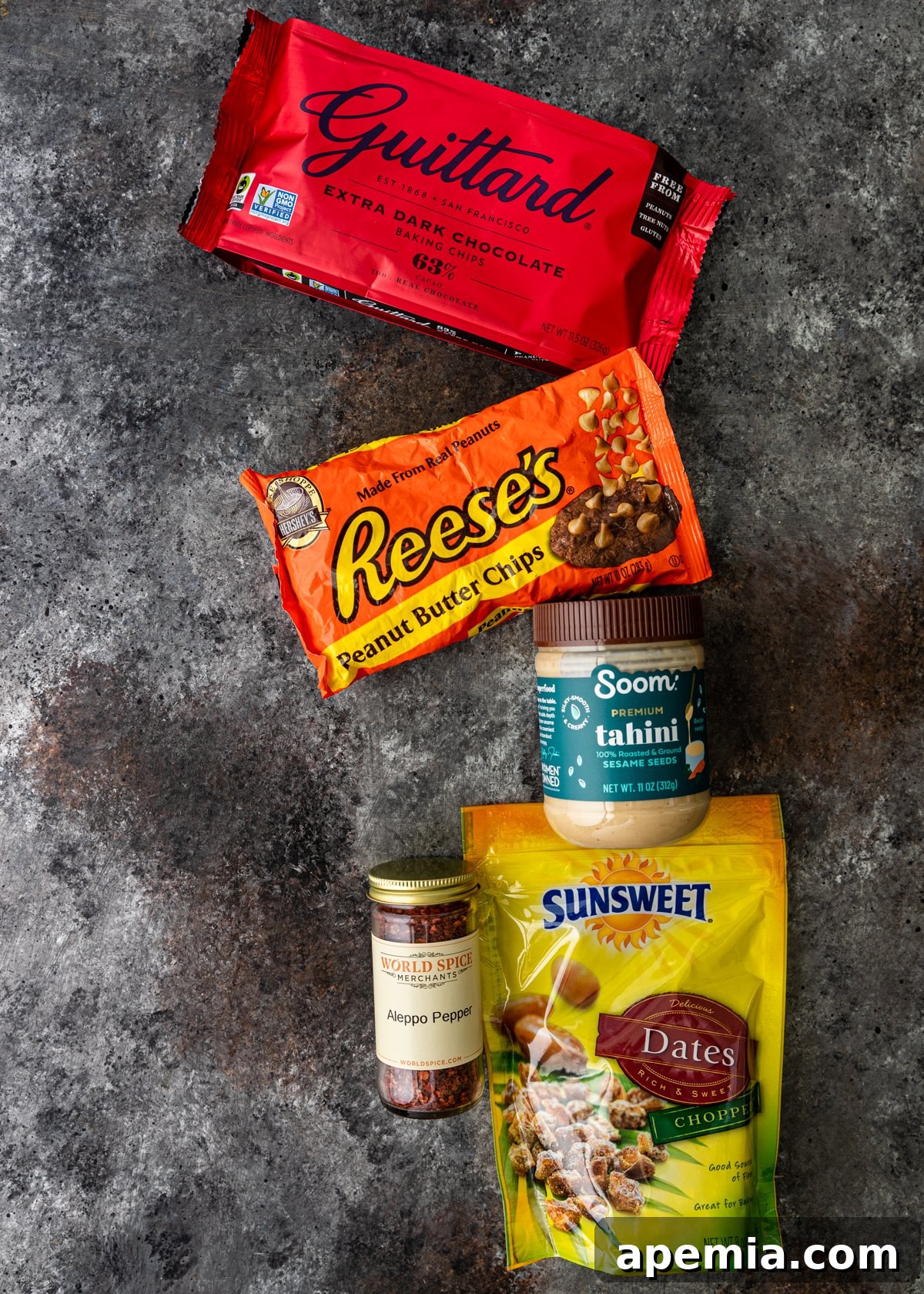 Overhead shot showing all the ingredients neatly laid out to make the Tahini Chocolate Bark recipe: dark chocolate, peanut butter chips, tahini, dates, and Aleppo pepper.
