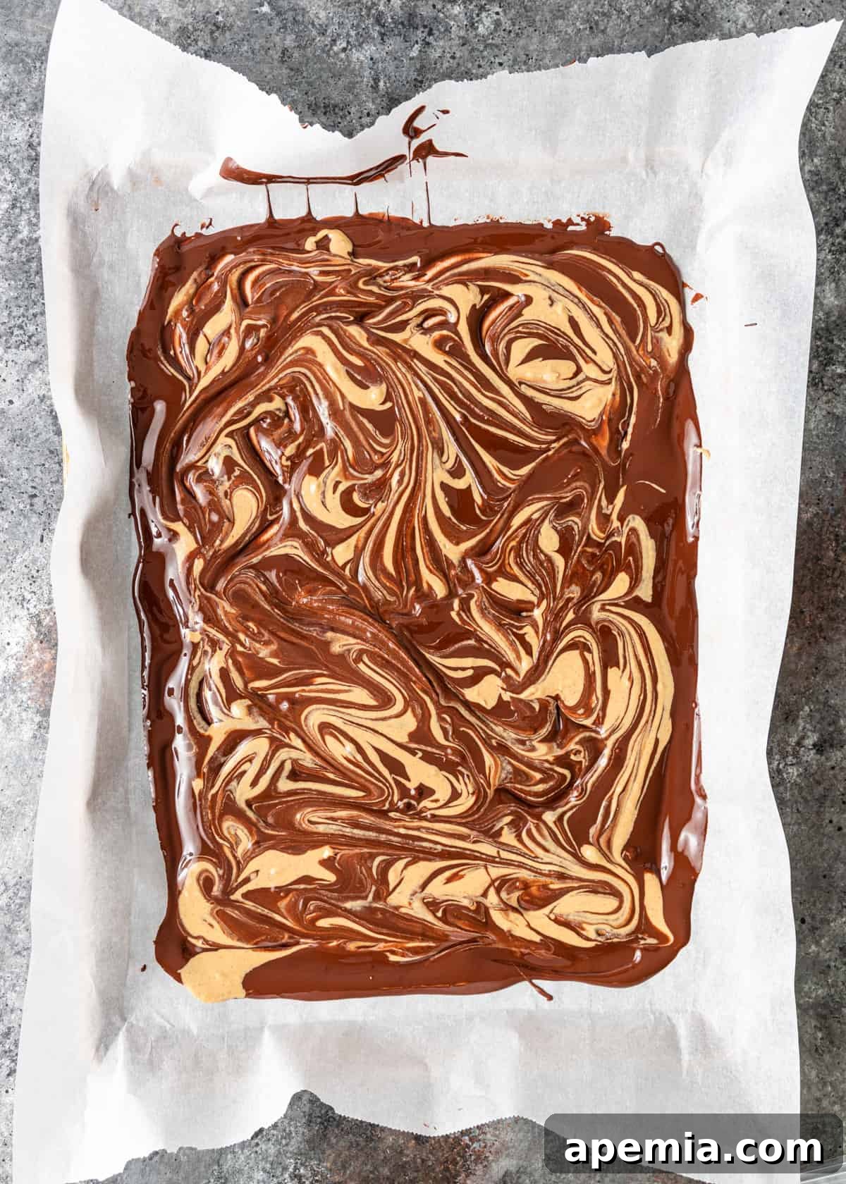 Overhead process shot illustrating how to swirl the tahini mixture into the melted dark chocolate to create a marbled effect.