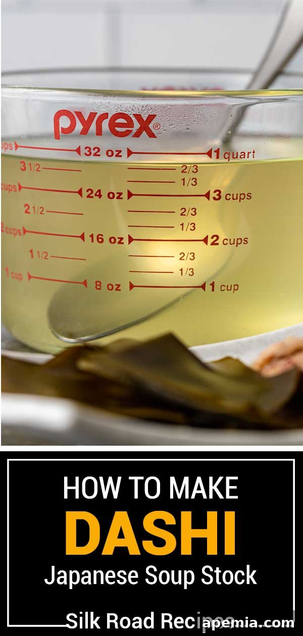 Side view of a glass measuring bowl filled with golden dashi stock, with light reflecting off its surface.