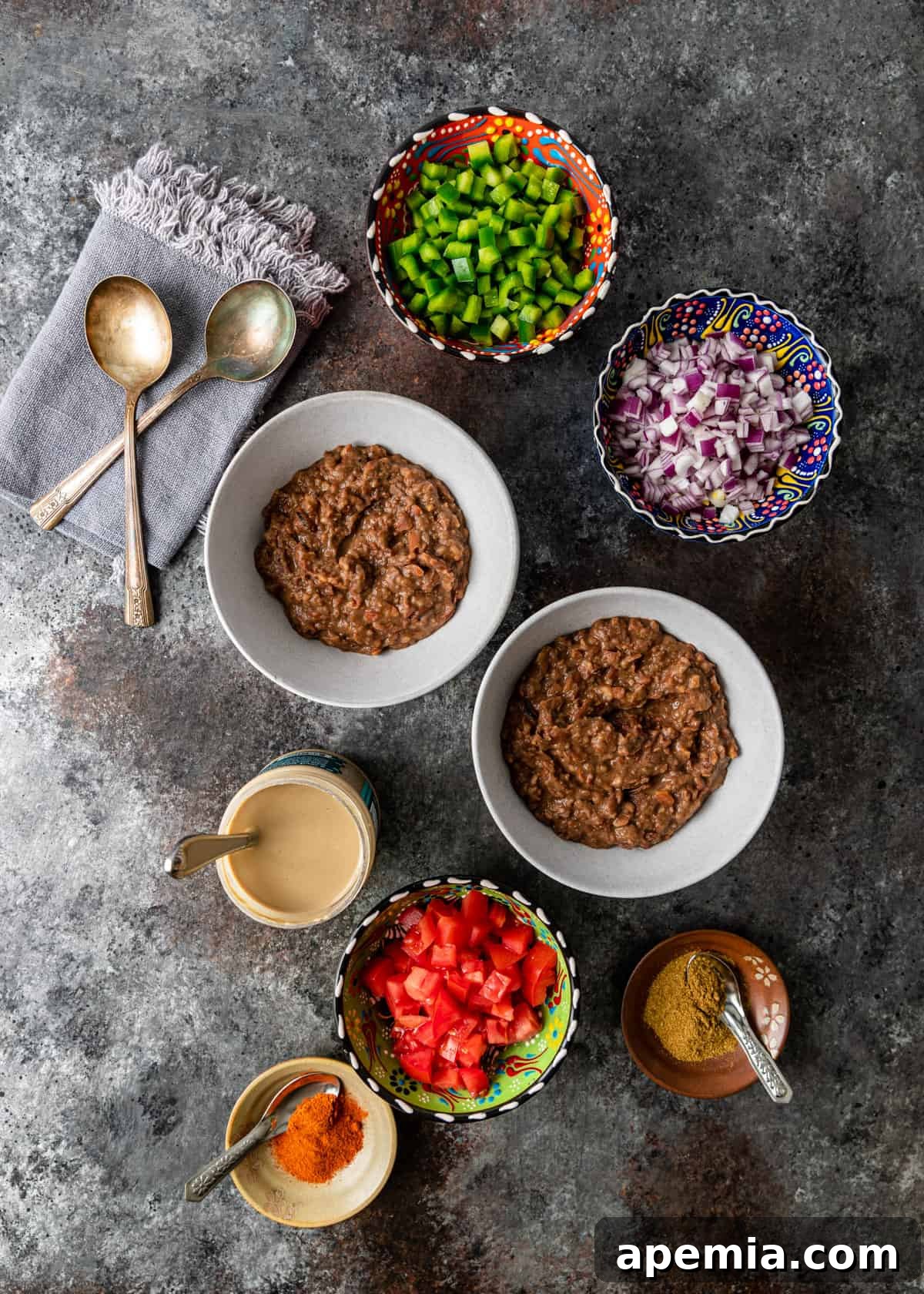overhead view of ful in bowls with toppings of chopped veg, spices and tahini