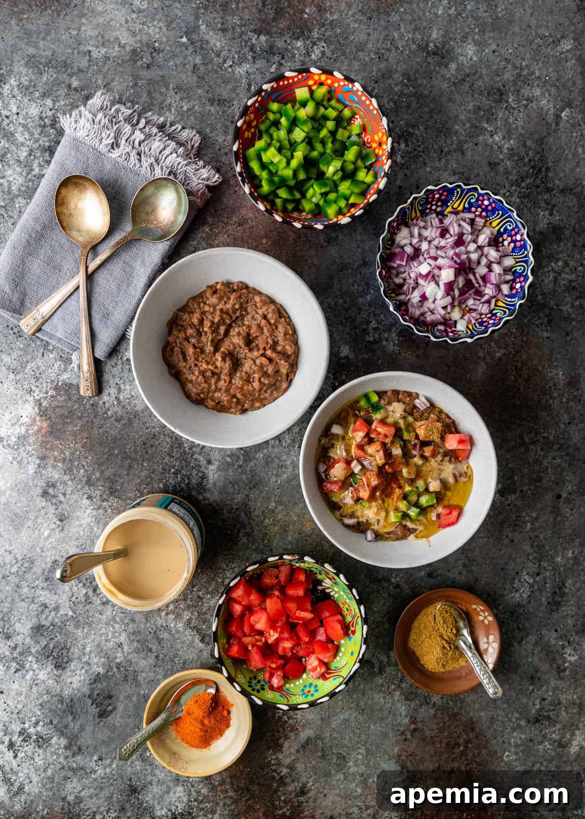 overhead view of ful in bowl with toppings of chopped veg, spices and tahini
