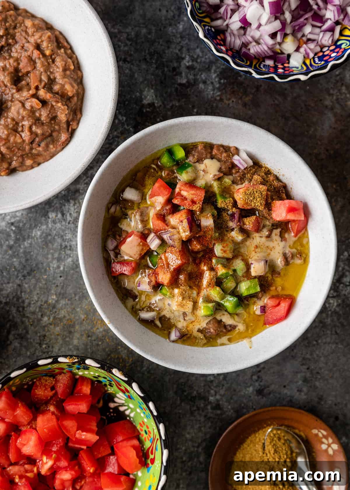 close up of overhead view of ful in bowl with toppings of chopped veg, spices and tahini