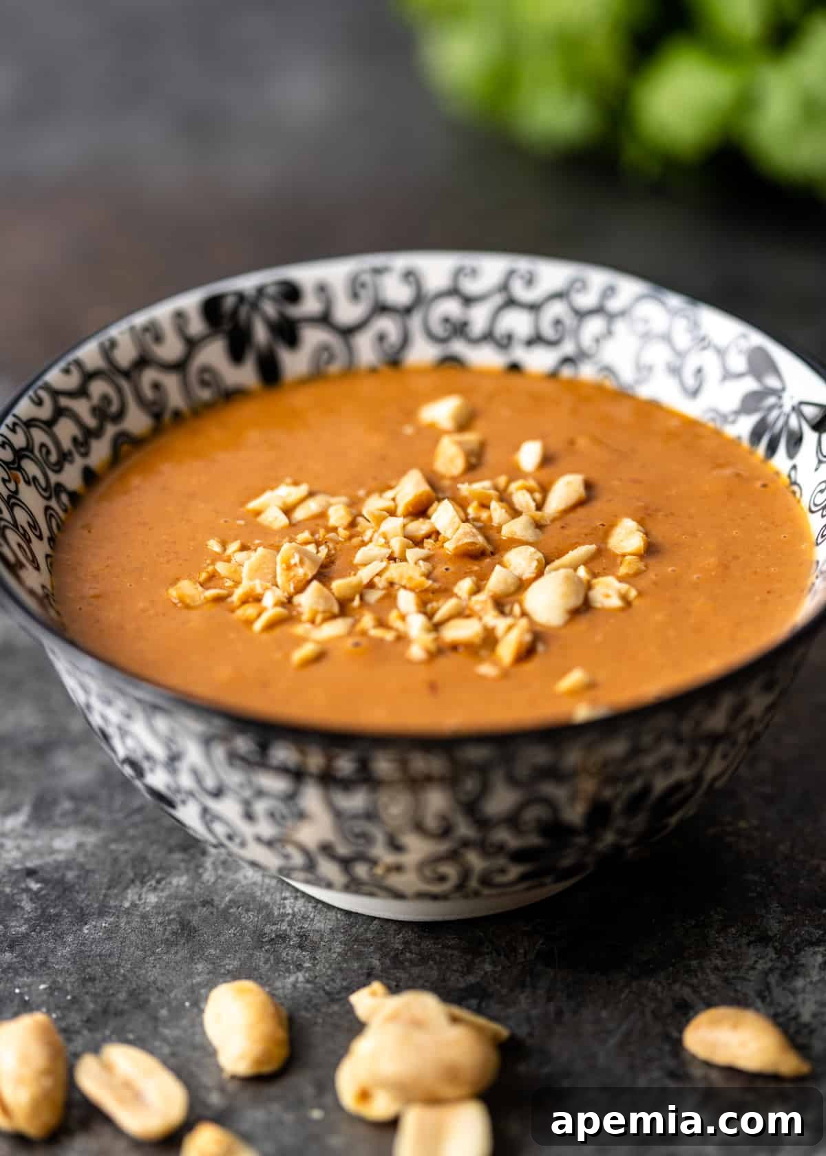 A black and white bowl filled with a generous serving of peanut sauce, highlighting its creamy texture.