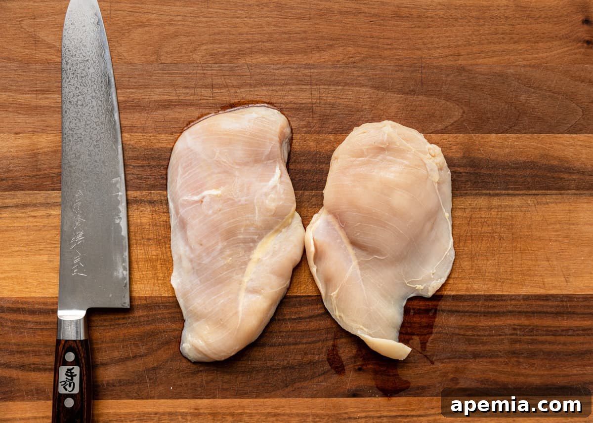 Slightly frozen chicken breast on a cutting board, making it easier to slice uniformly.