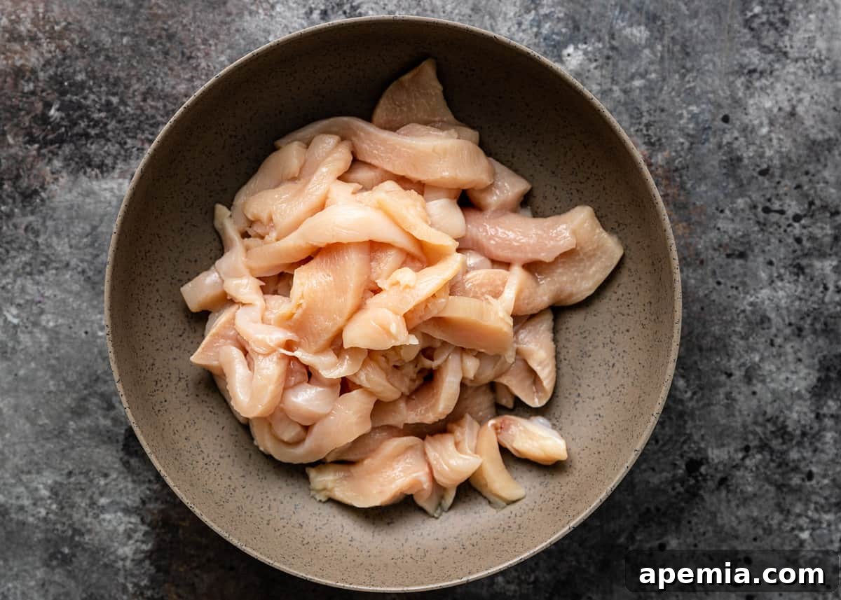 Uniformly sliced chicken breast pieces in a bowl, ready for marinating.