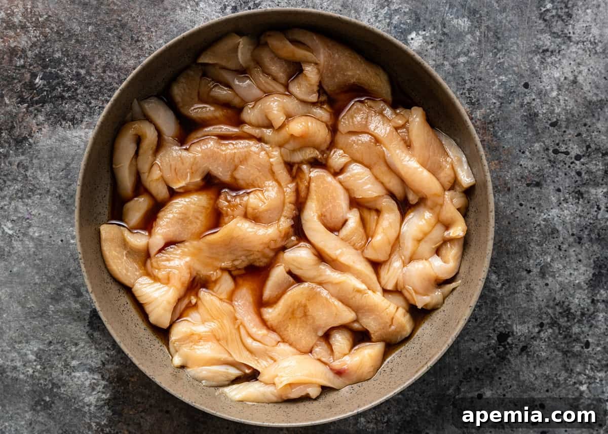 Chicken marinating in a bowl with soy sauce and water, absorbing flavors.