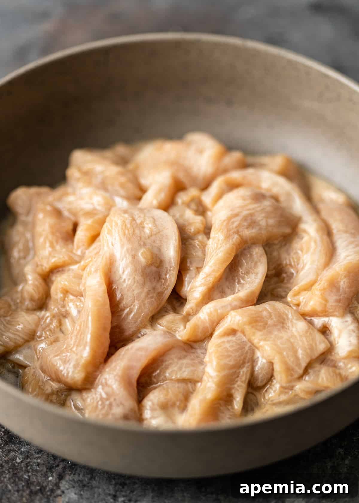 Closeup of beautifully velveted chicken pieces, ready for stir-frying.