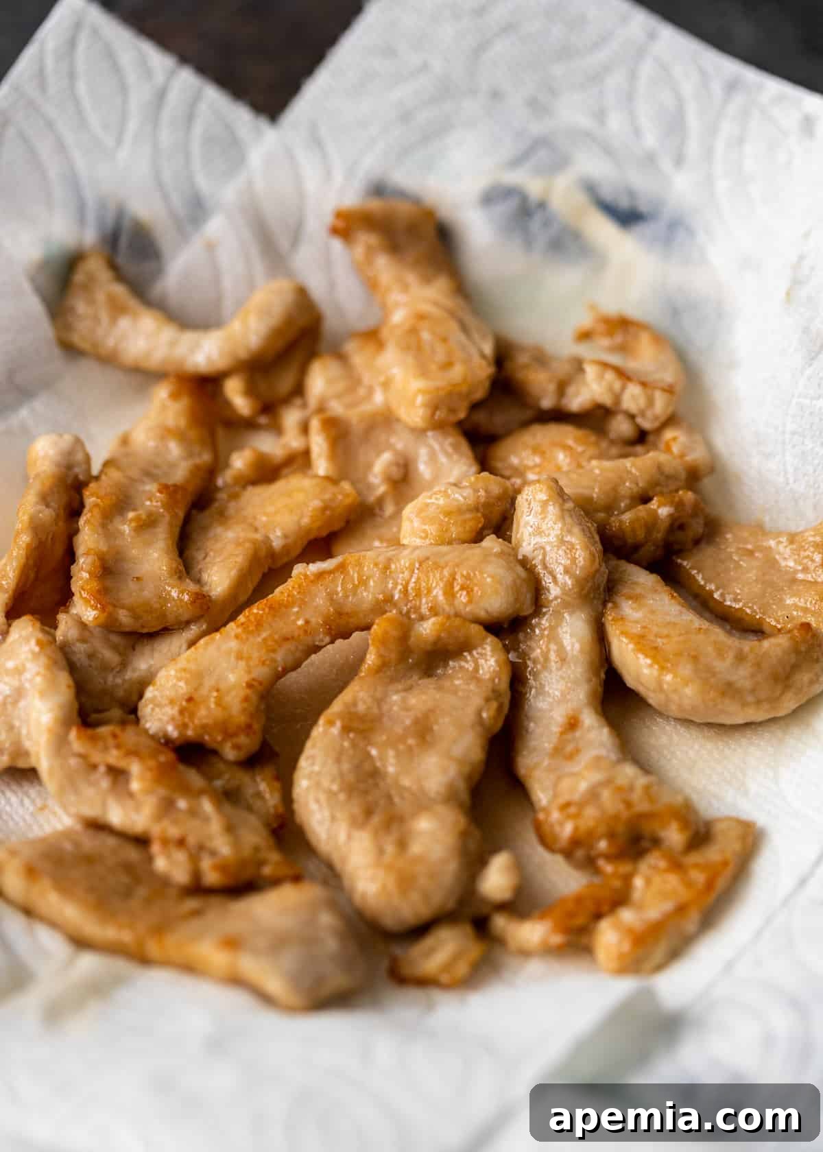 Marinated chicken pieces patted dry on paper towels, ready for pre-cooking.
