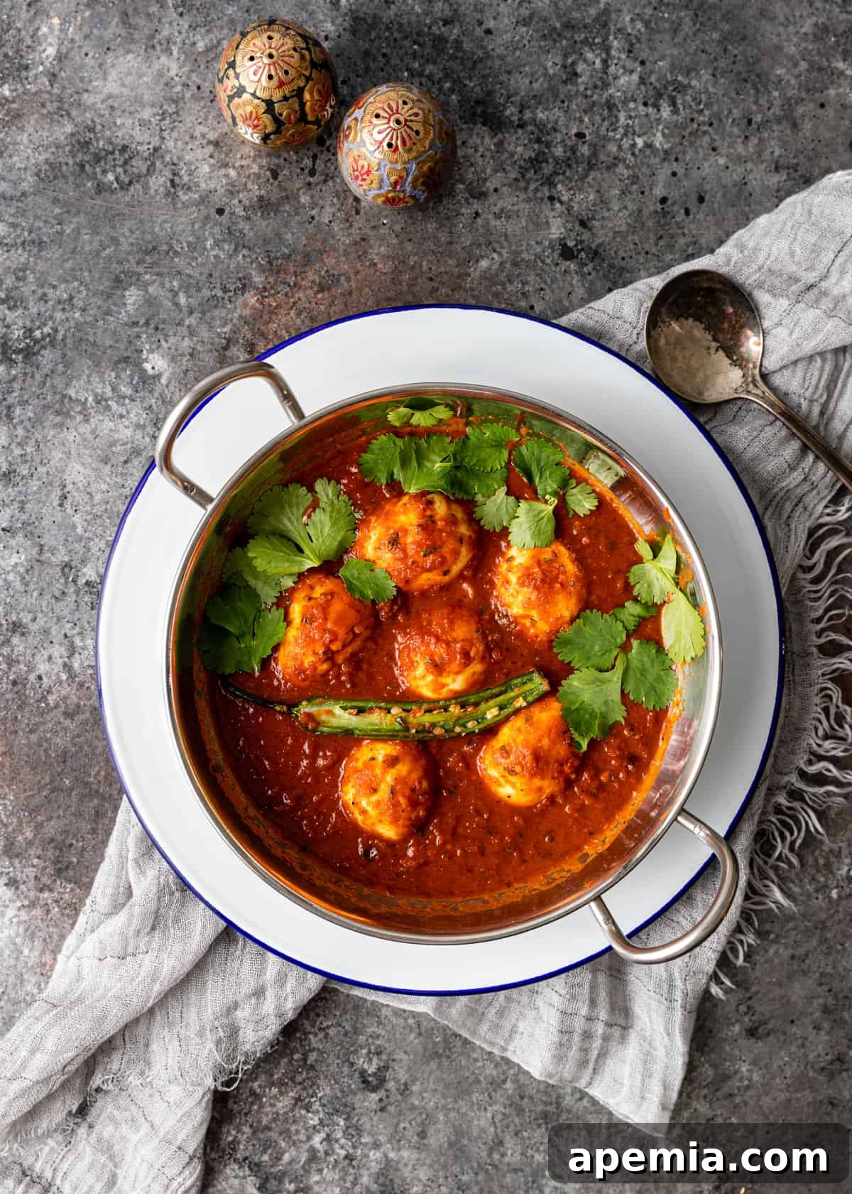 overhead: egg curry in pot on white plate