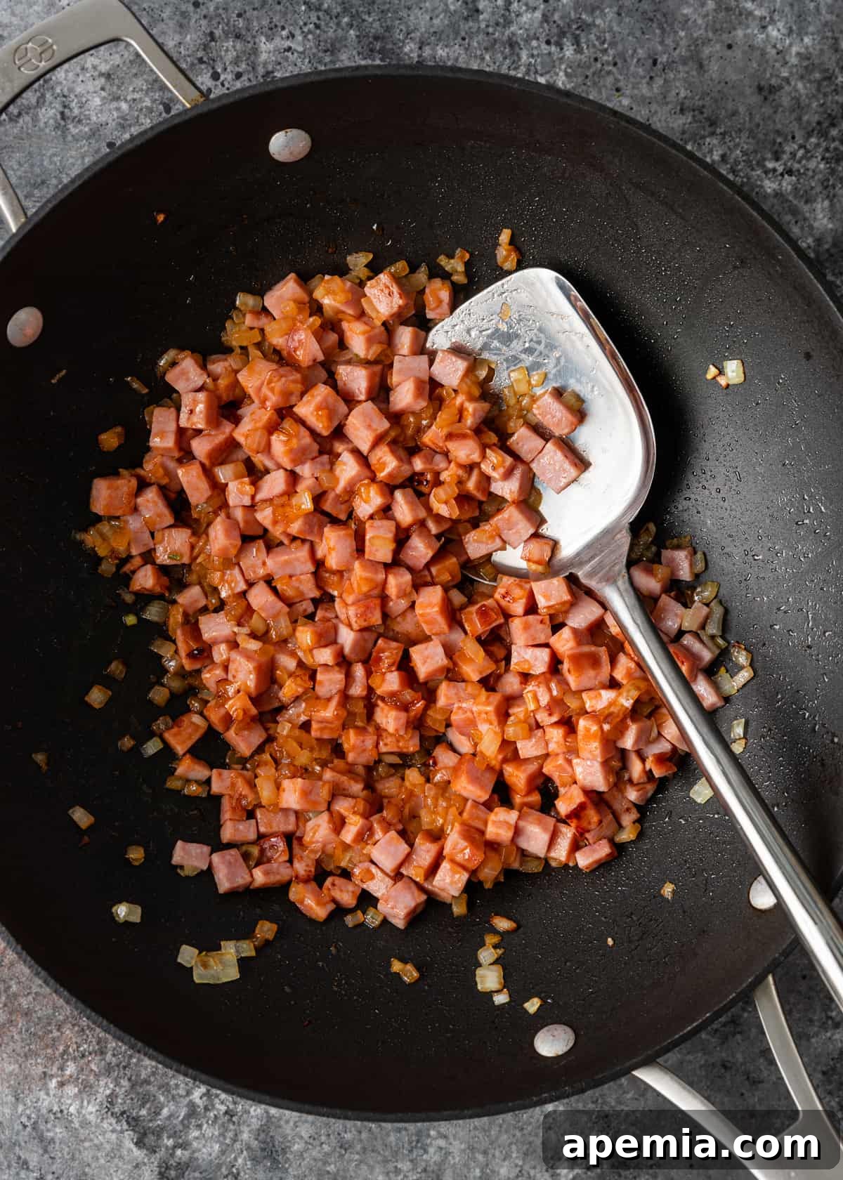 Process shot: Diced onions and cubed pork being stir-fried in a hot wok, releasing aromatic steam.