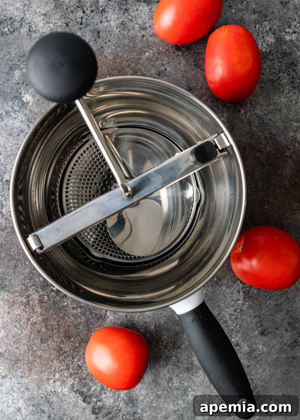 A manual tomato strainer in action, processing fresh tomatoes.