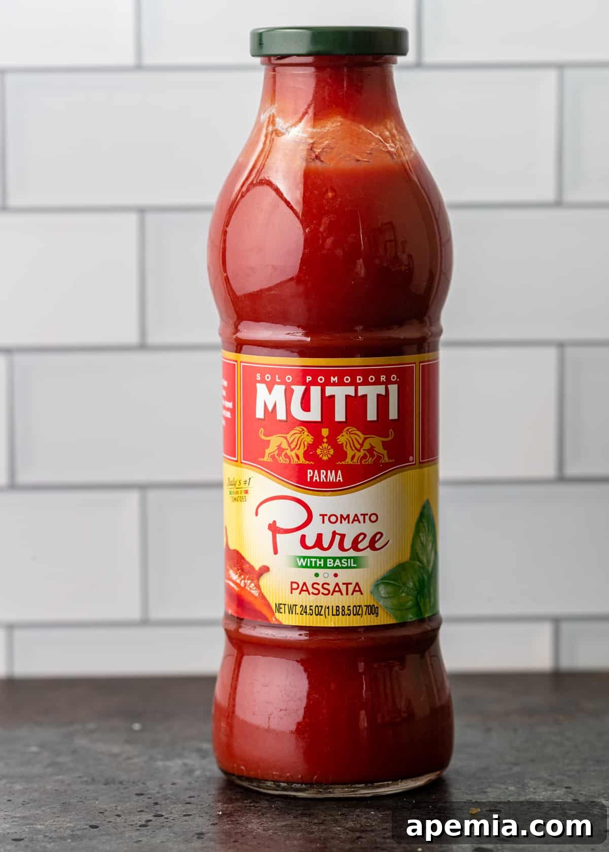 A glass bottle of passata on a kitchen counter.