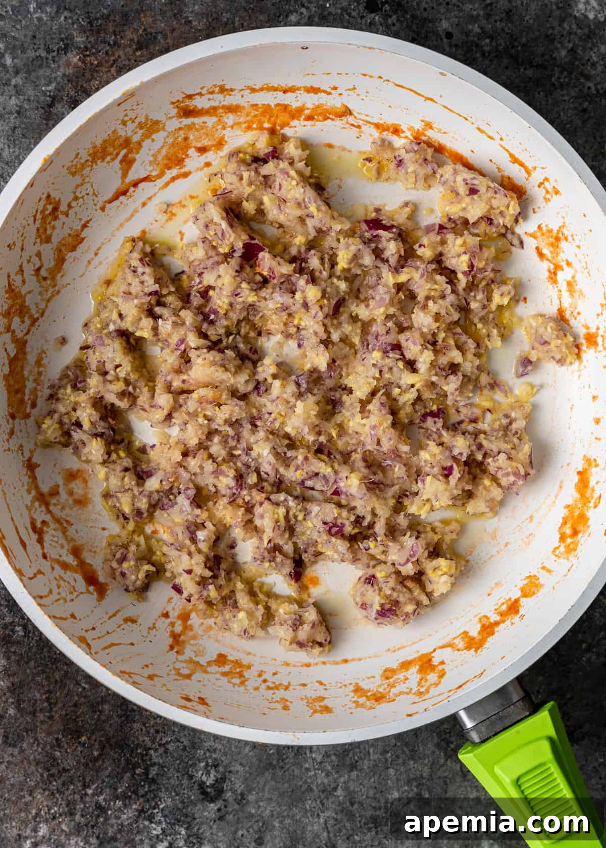 Sweet Heat Tomato Chutney 7 Overhead process shot: Finely chopped aromatics (onion, garlic, ginger) sautéing in oil in a skillet.
