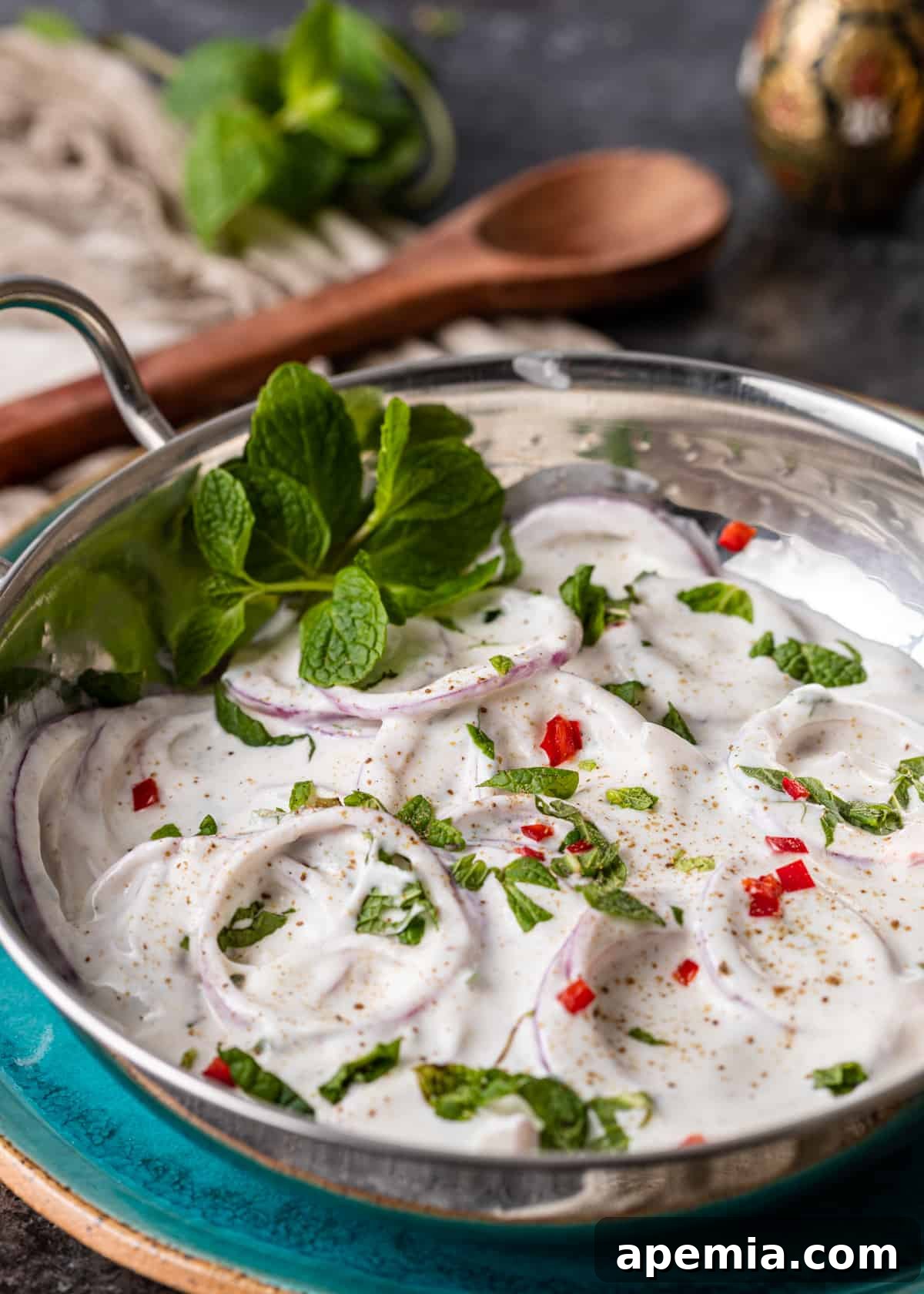 Side view of creamy Onion Raita in a white bowl, garnished with fresh mint leaves.