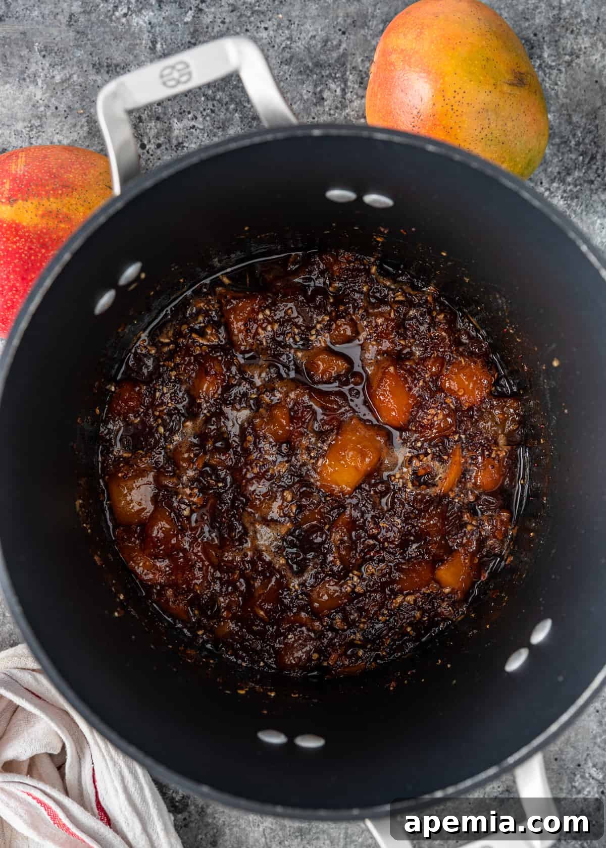 A pot filled with the mango chutney, now beautifully cooked down to a thick, syrupy consistency, indicating it's nearly ready.