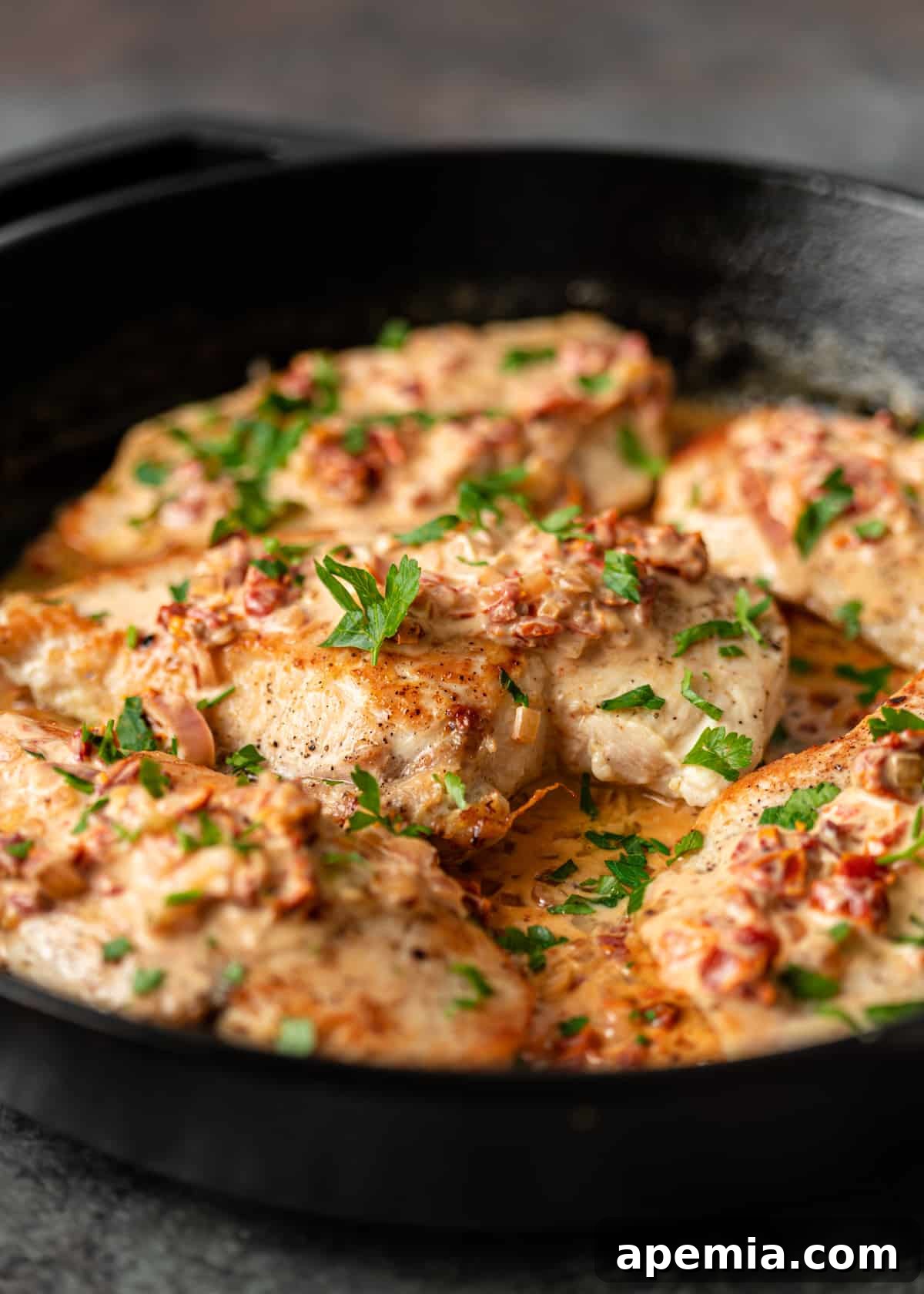 Side view of a skillet filled with Creamy Tuscan Chicken and rich sauce