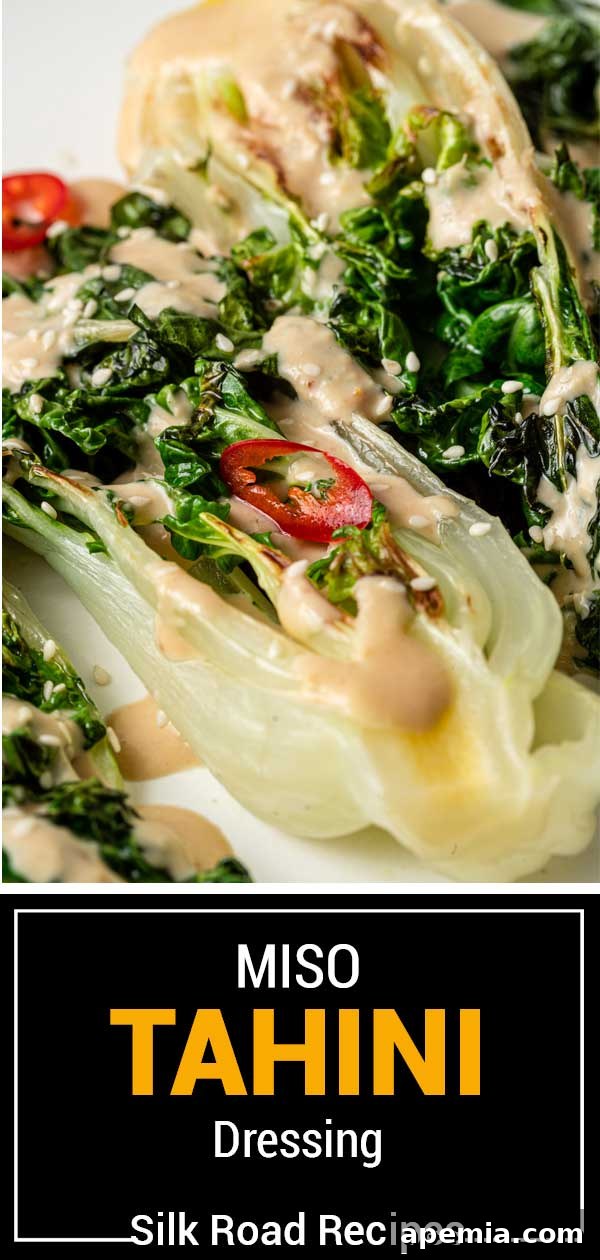 A vibrant green salad with small red peppers, generously drizzled with creamy Miso Tahini Dressing, with the text 'Miso Tahini Dressing' overlaid, emphasizing the dish.