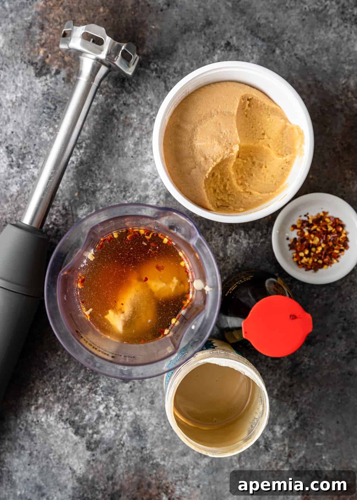 A simple set of kitchen equipment, including a blender, measuring cups, and spoons, ready for preparing Miso Tahini Dressing on a clean countertop.