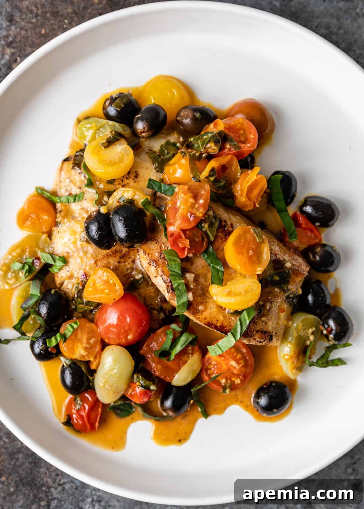 Overhead shot of a beautifully plated Mediterranean pan-seared cod dish with rich tomato and olive sauce.