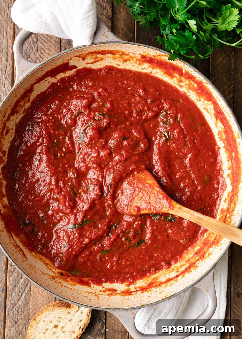 overhead: cooking spaghetti sauce in a large skillet with a wooden spoon visible