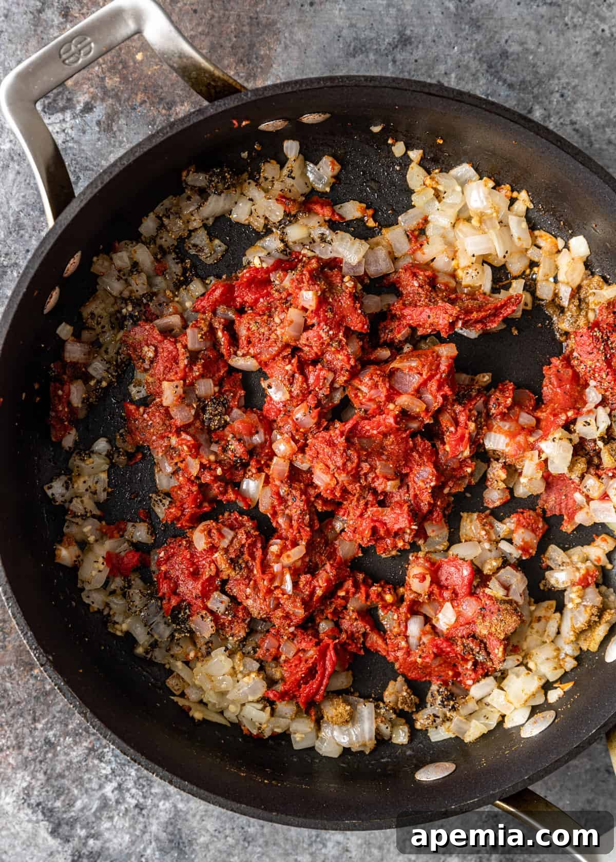 starting Egyptian pea stew with onions and tomato paste in a skillet