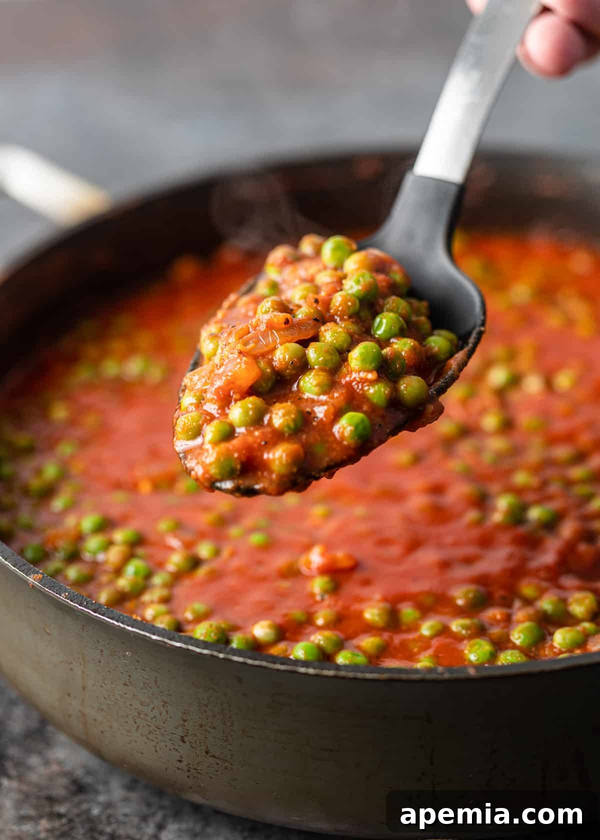 close up of a spoonful of Egyptian pea stew over a large pot