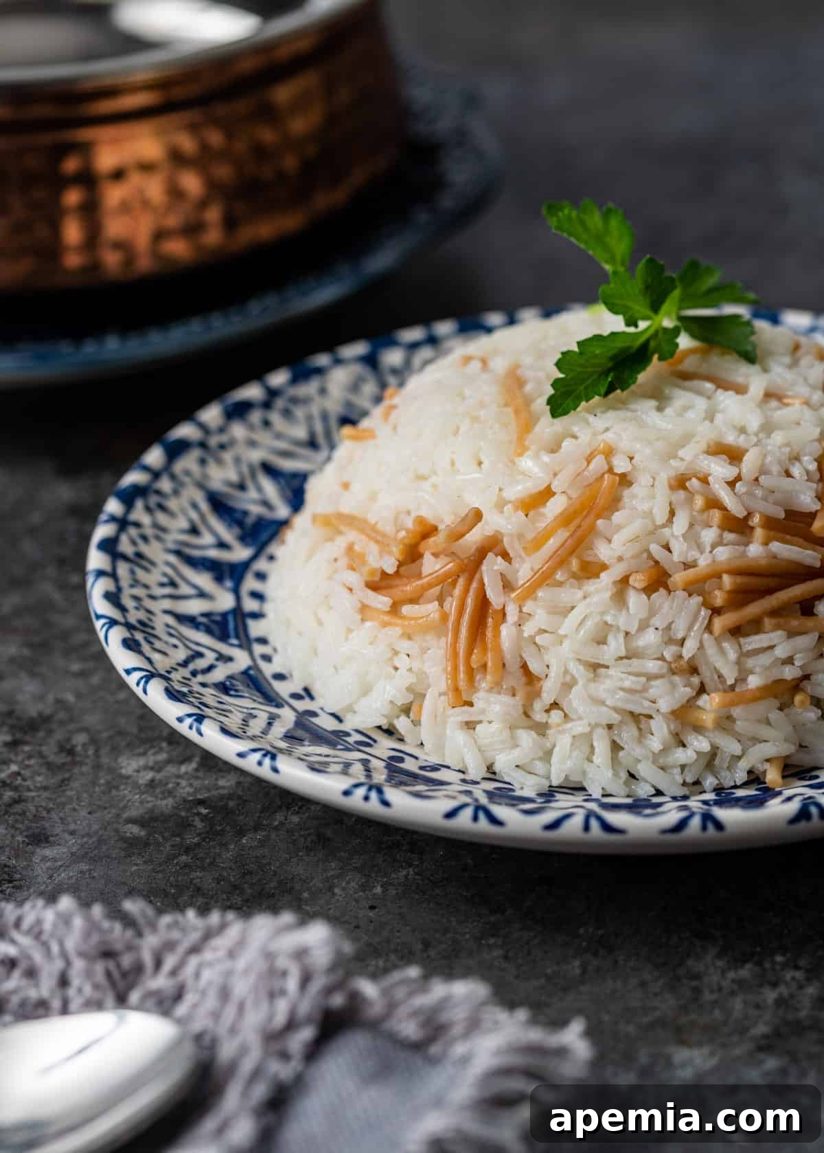 A beautifully arranged blue and white plate showcasing Egyptian rice with golden vermicelli and fresh green herbs.