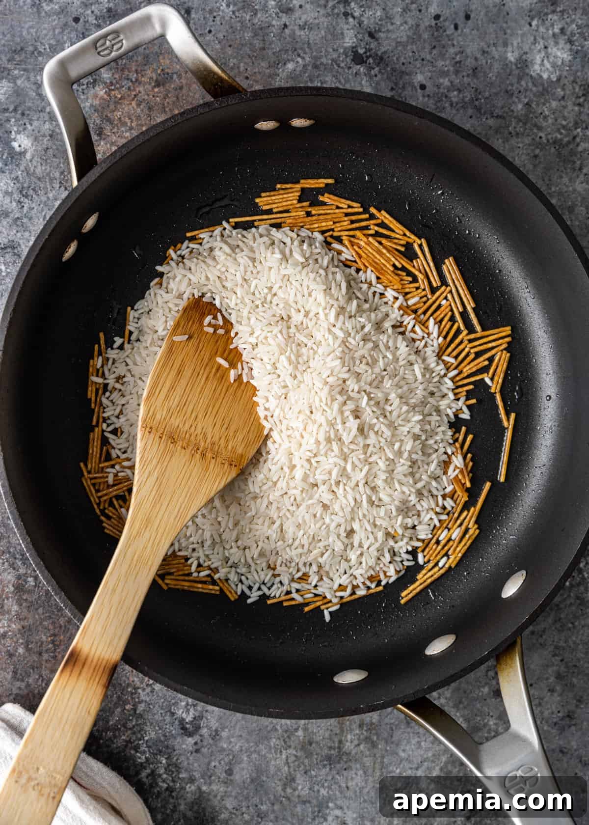 A close-up view of vermicelli being stirred and toasted in a skillet before adding rice.