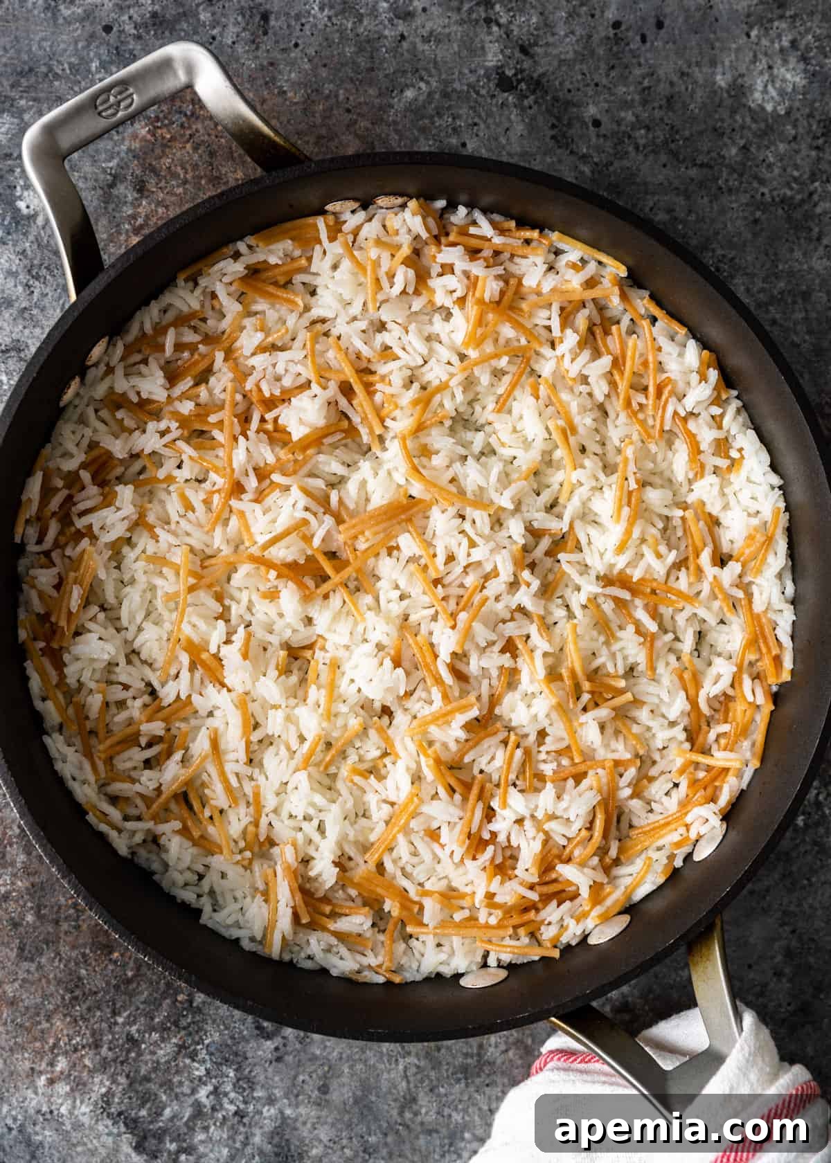 Top-down view of perfectly cooked Egyptian rice with vermicelli in a skillet, ready to be fluffed.