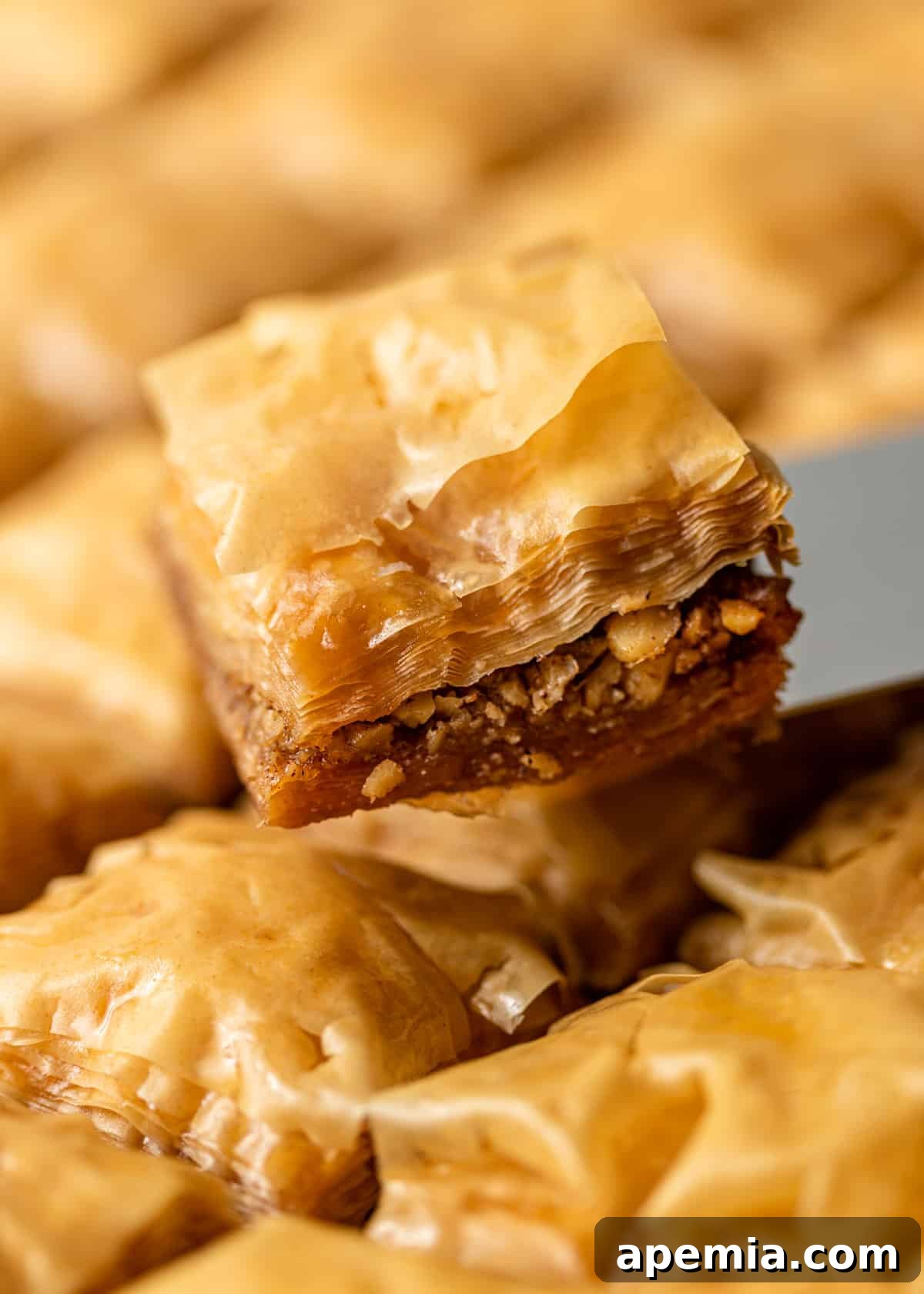 Sweet Greek Baklava Made Simple 3 close up of a slice of Greek baklava being lifted out of a tray of baklava