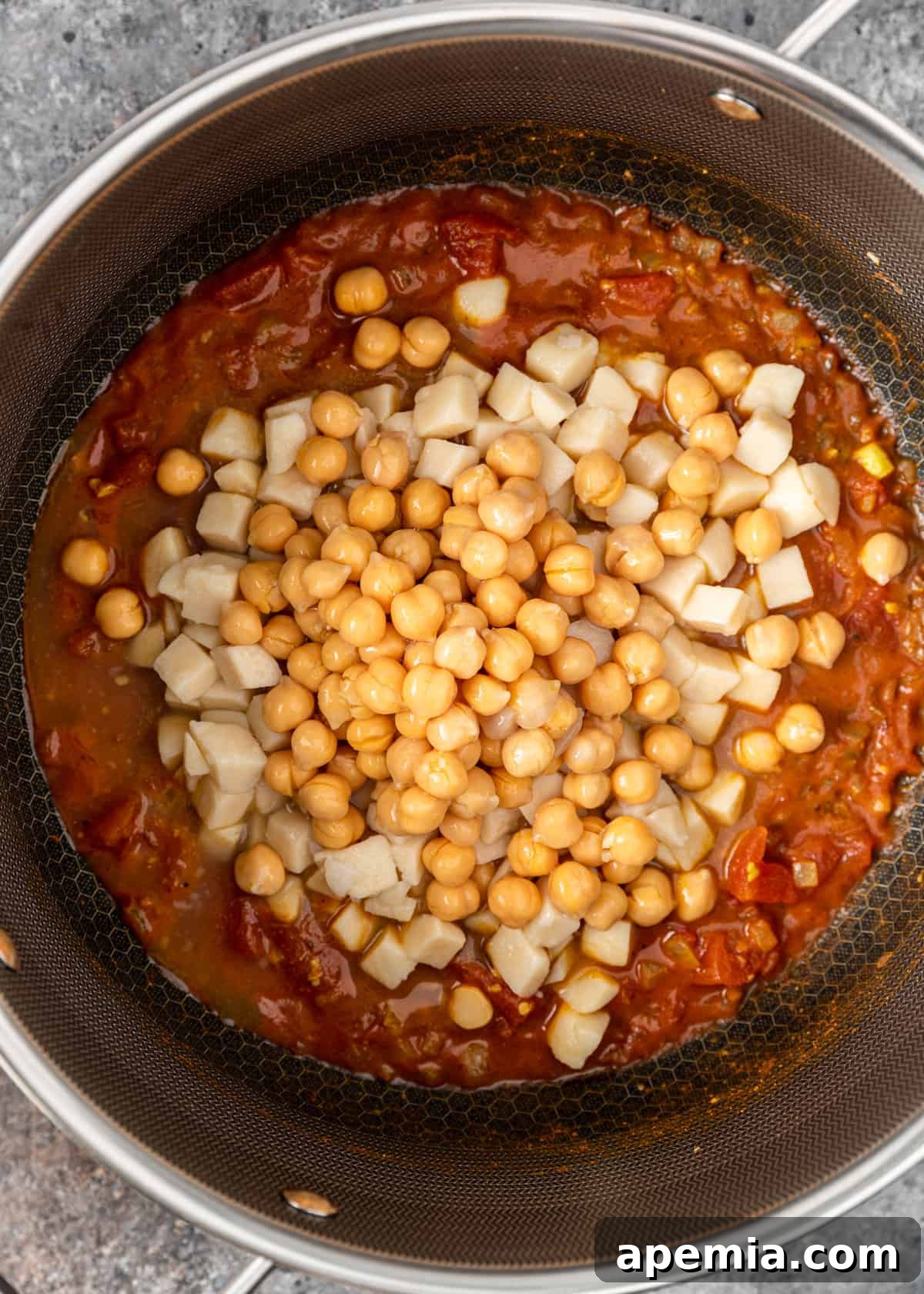 overhead view of tomato sauce, potatoes, and chickpeas in a pot