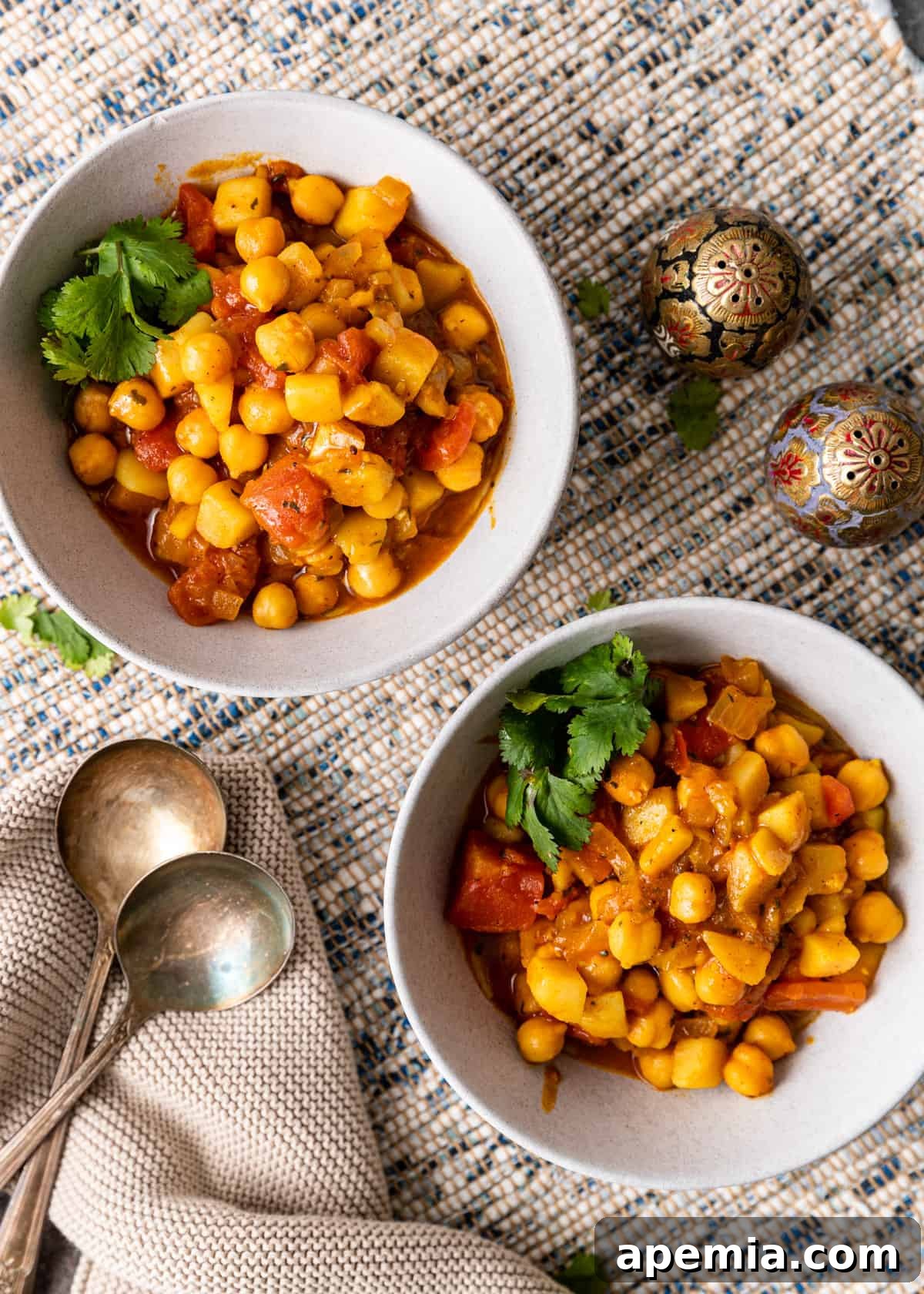 overhead view of two bowls of chickpea curry with parsley garnish