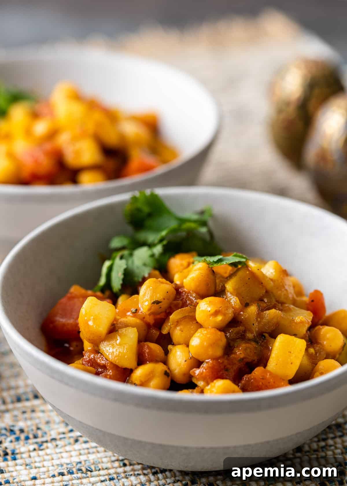 chickpea curry in a white bowl with herby garnish