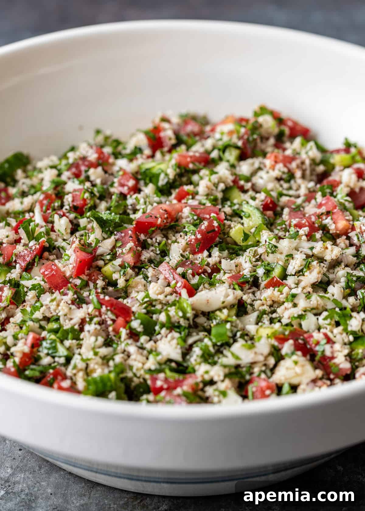 a large white bowl full of cauliflower tabbouleh